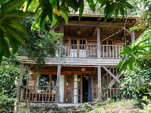 A wooden two-story building with a balcony, surrounded by dense foliage. - Cay Sao Hill Resort Phu Quoc (Phu Quoc)