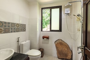 A bathroom with a toilet, sink, shower, and a window with a view of greenery. - Cay Sao Hill Resort Phu Quoc (Phu Quoc)