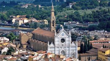 Una iglesia histórica con una torre campanario destacada y un amplio ventanal circular, rodeada de una zona urbana densamente construida y arquitectura variada.