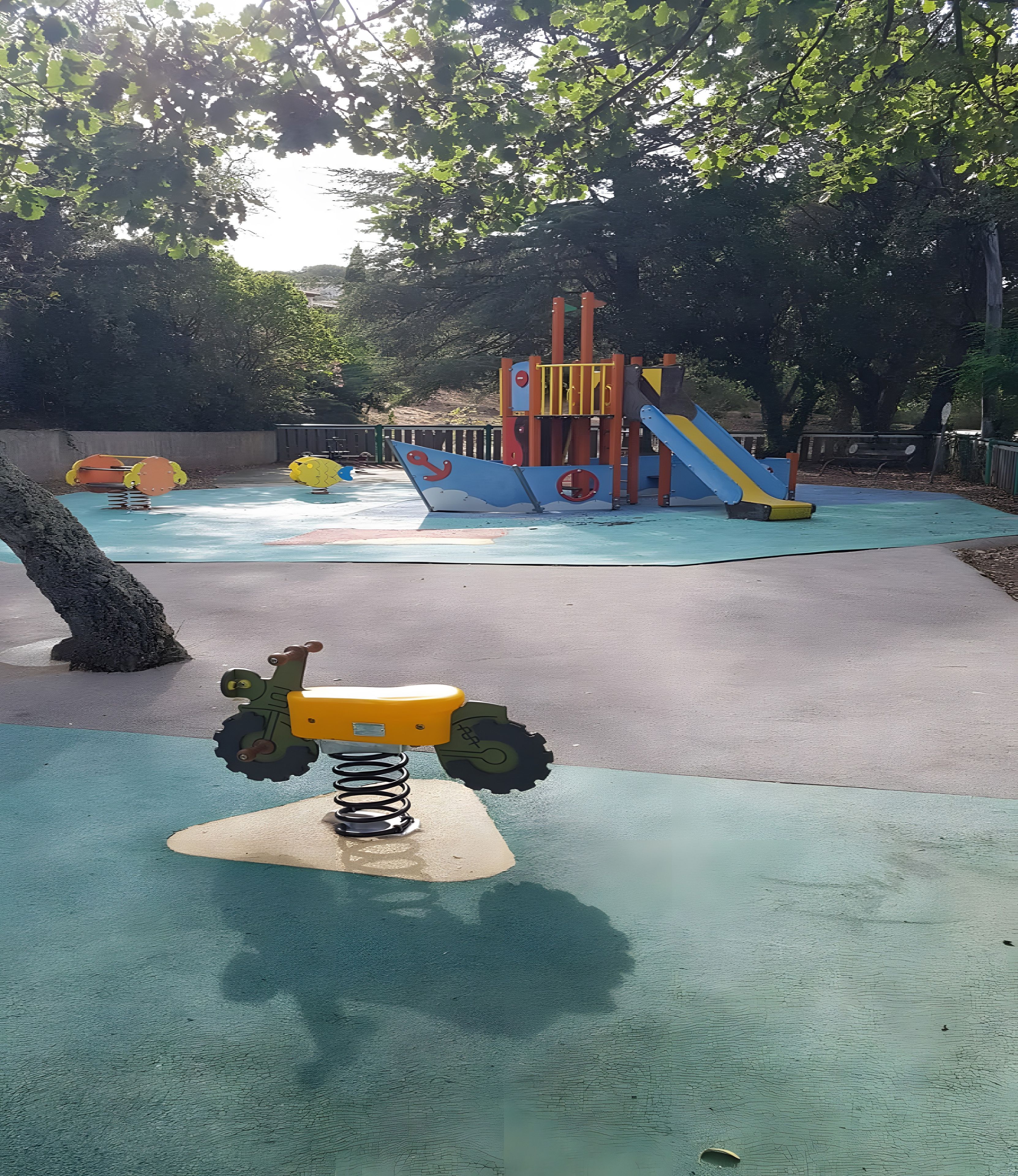 A playground with a seesaw, climbing structures, and a slide.