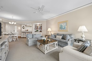 A spacious living room with a ceiling fan, a dining area with a chandelier, and a kitchen with white cabinets. - Palmetto Dunes Condo with Ocean Views, Pool, Hot Tub & Private Beach Boardwalk (Hilton Head Island)