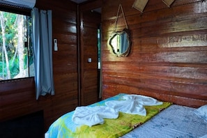 A wooden room with a bed, a window with curtains, and a mirror on the wall. - Pousada Carijó da Serra (Santarém)