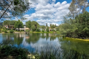 Un cadre paisible au bord du lac, agrémenté d’un belvédère, d’un petit bâtiment et d’une végétation luxuriante.