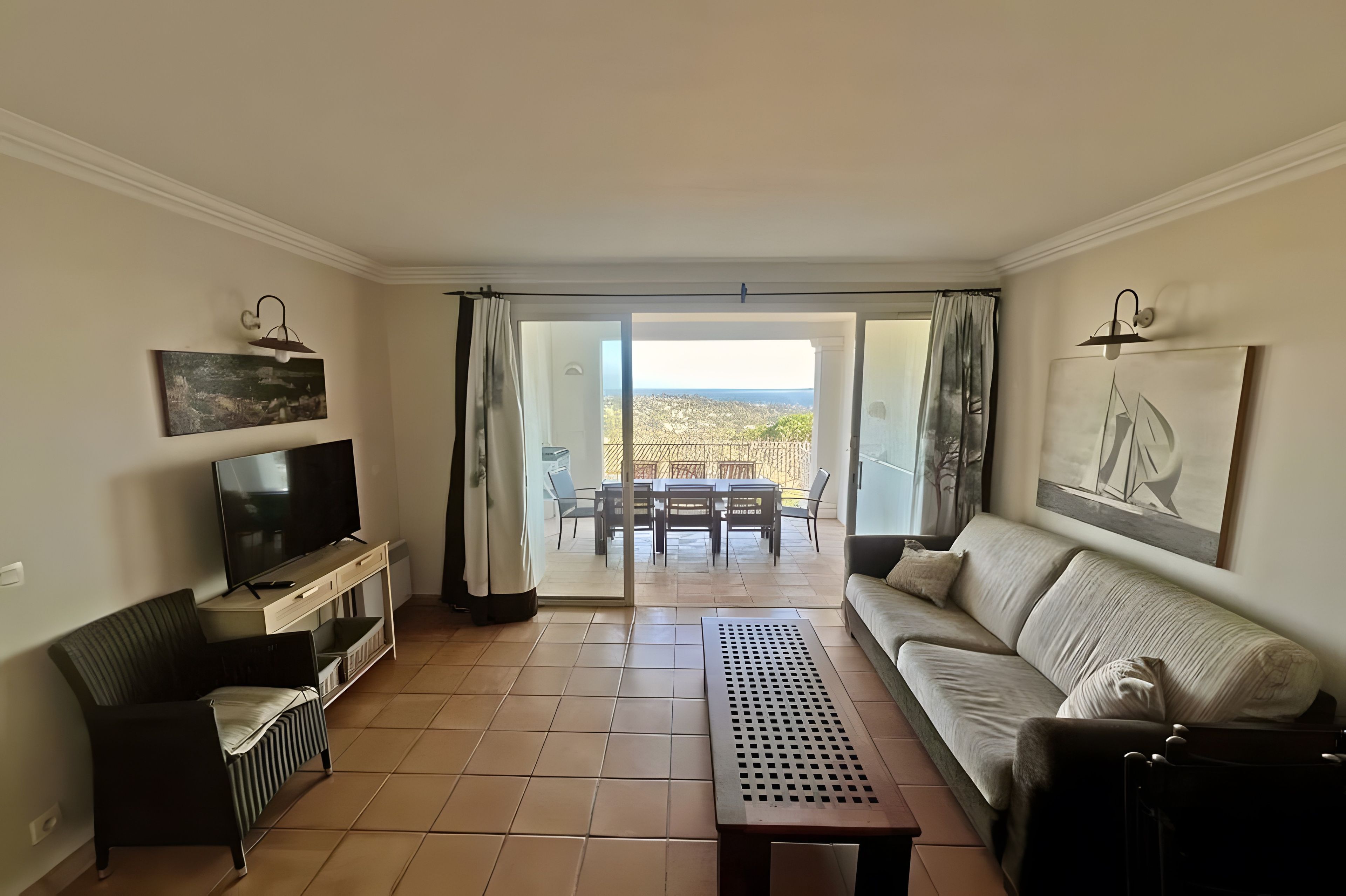 A living room with a television, sofa, and a view to an outdoor patio.