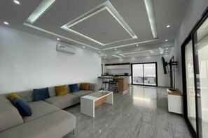Una sala de estar moderna con un sofá, una mesa de centro y una cocina al fondo.