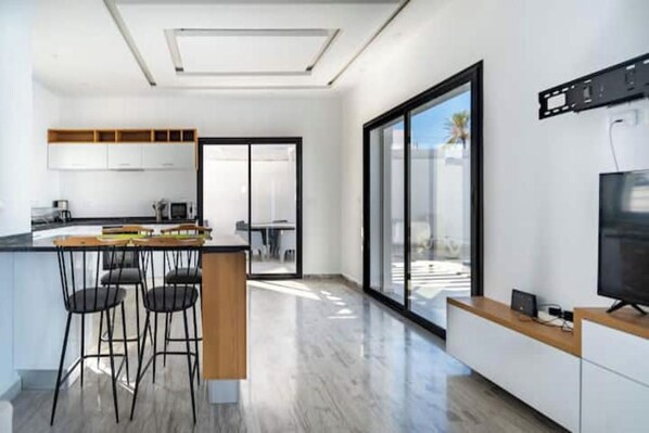 Una cocina moderna con barra, ventanas amplias y televisor de pantalla plana.