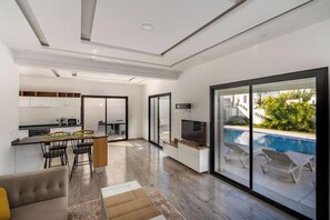 Un interior moderno con cocina, comedor y un área de descanso junto a la piscina.