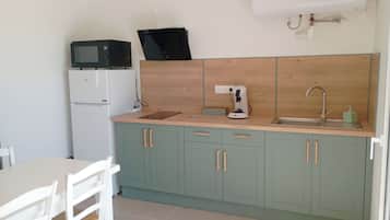 A compact kitchen with a microwave, coffee maker, and sink.