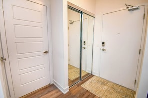 A hallway with a white door, a mirrored closet door, and a wooden floor. - Luxury 2BD Condo Friday Harbour Resort (Innisfil)