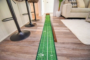 A room with a green measuring tape laid out on the floor, two black bar stools, a white sofa, and a white rug. - Luxury 2BD Condo Friday Harbour Resort (Innisfil)