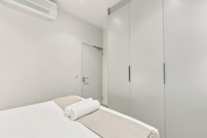 Ein Schlafzimmer mit einem Bett, einem Kleiderschrank und einer Wandklimaanlage.