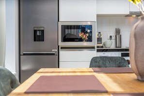A modern kitchen with a stainless steel refrigerator, a Bosch microwave, and a water dispenser. - Elevated City Stay | City Centre and Views (Cape Town)