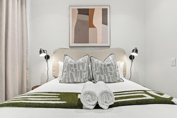 Een opgemaakt bed met een gestreept kussen, een hoofdbord en twee bedlampen.