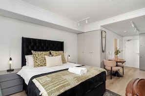 Ein modernes Schlafzimmer mit einem großen Bett, Nachttischen, einem Schreibtisch und einem Kleiderschrank.