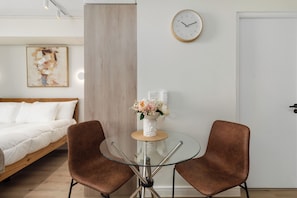 Ein modernes Schlafzimmer mit einem Bett, einem Glastisch mit Stühlen, einer Uhr und einem Bild an der Wand.