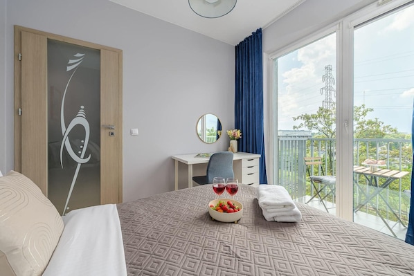 A hotel room with a bed, a desk, a chair, a balcony with a view, and a window. - Apartment near Młynów Metro (Warszawa)