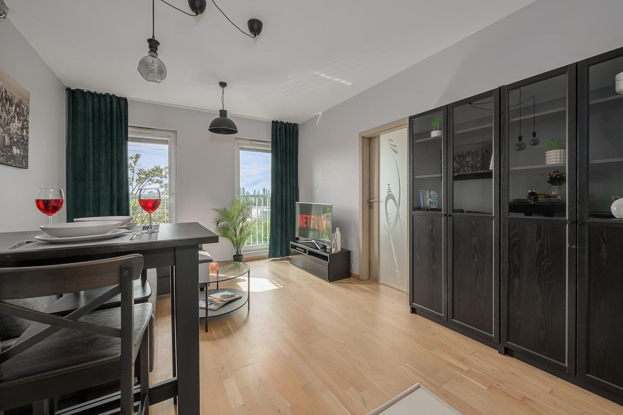 A modern kitchen with a dining table, chairs, and a TV displaying the Netflix logo.