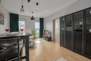 A modern kitchen with a dining table, chairs, and a TV displaying the Netflix logo. - Apartment near Młynów Metro (Warszawa)