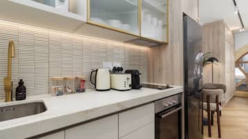Una cocina moderna con horno empotrado, refrigerador y cafetera sobre la encimera.