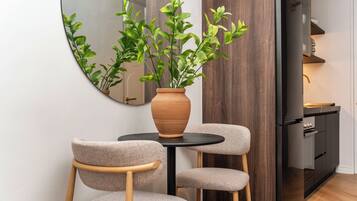 A modern kitchen with a round table, two chairs, a potted plant, and a mirror on the wall.