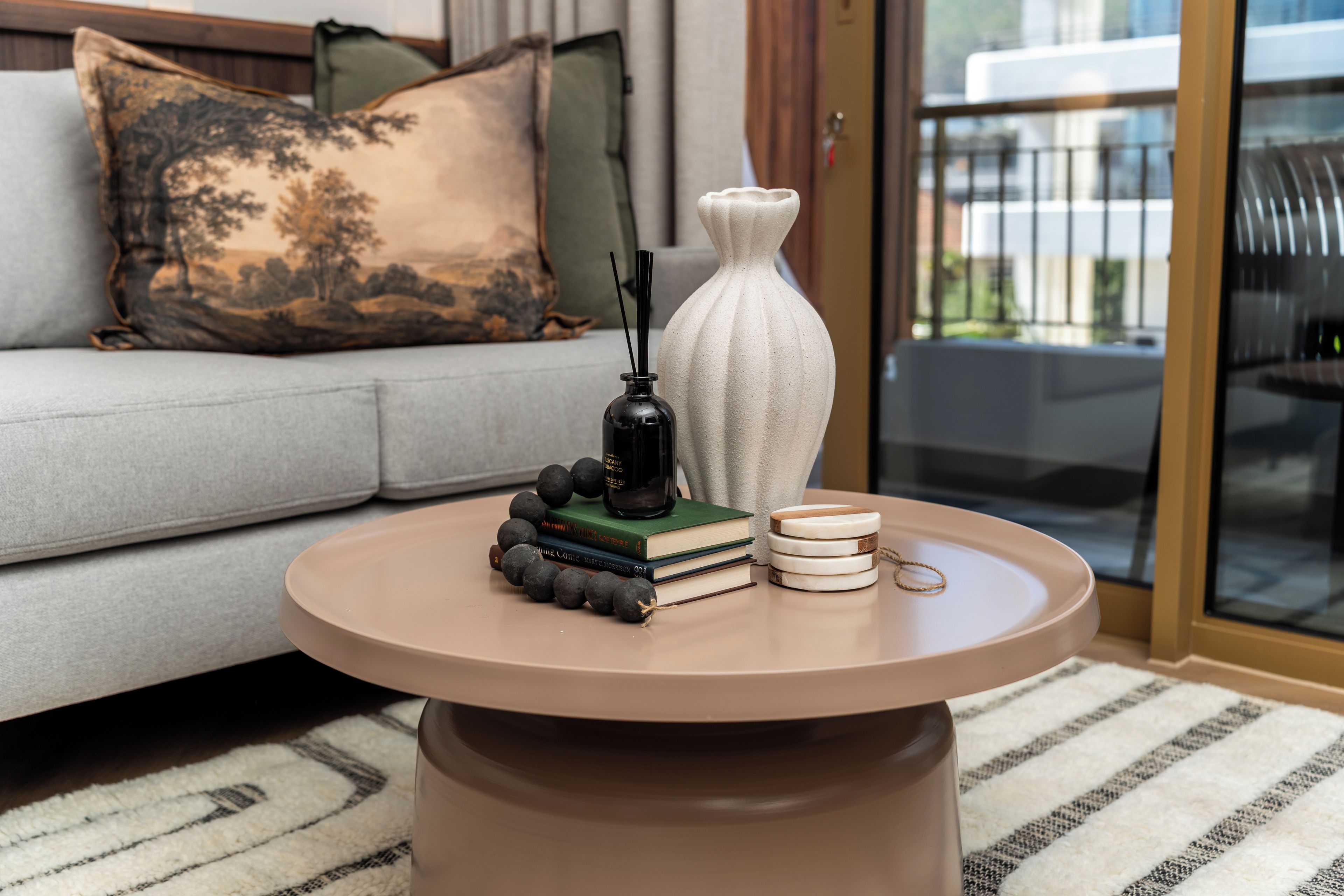 A round coffee table with a vase, books, and decorative items.