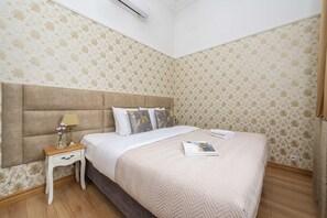 Ein Schlafzimmer mit Bett, Nachttisch, Lampe und Zierkissen.