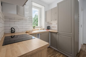 Eine moderne Küche mit einer Holz Arbeitsplatte, einem eingebauten Herd und grauen Schränken.