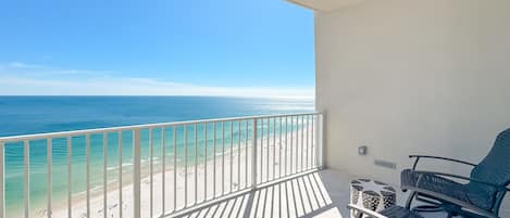 A balcony with a view of the beach and ocean.