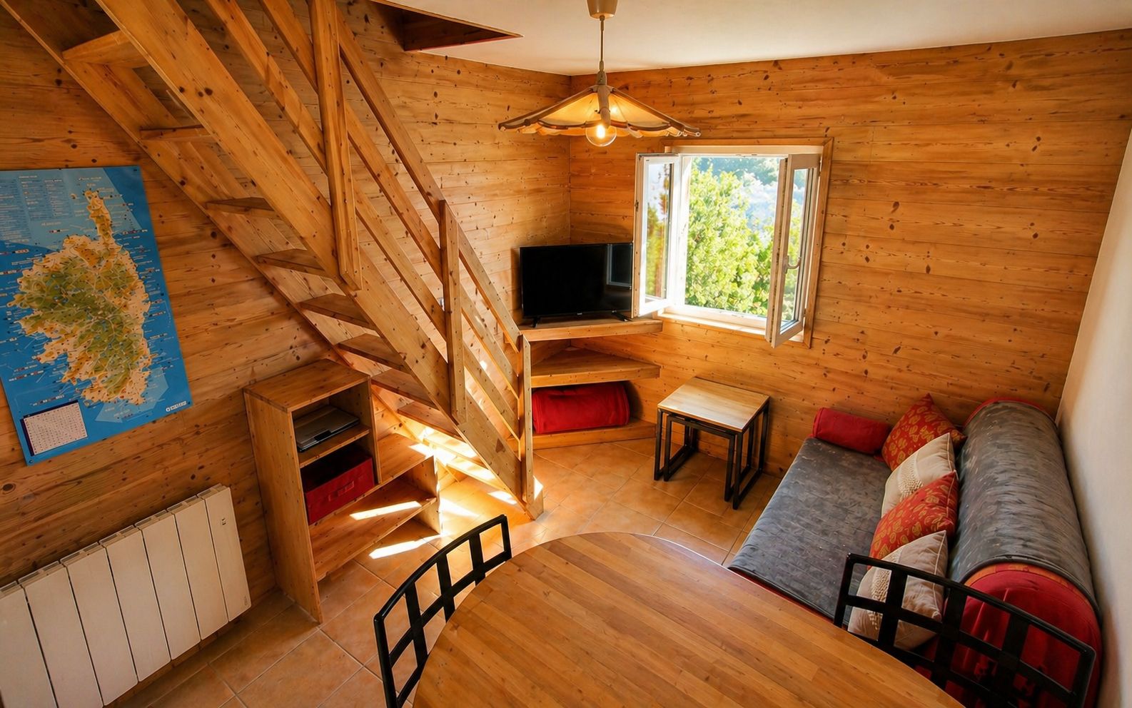 A wooden interior with a staircase, a television, a sofa, and a map on the wall.