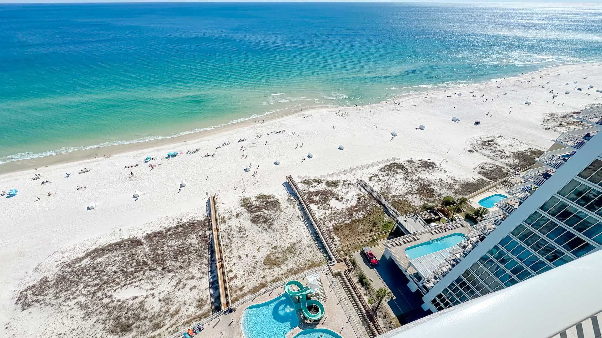 An aerial view of a beach with a pool area, including a water slide and a pool.