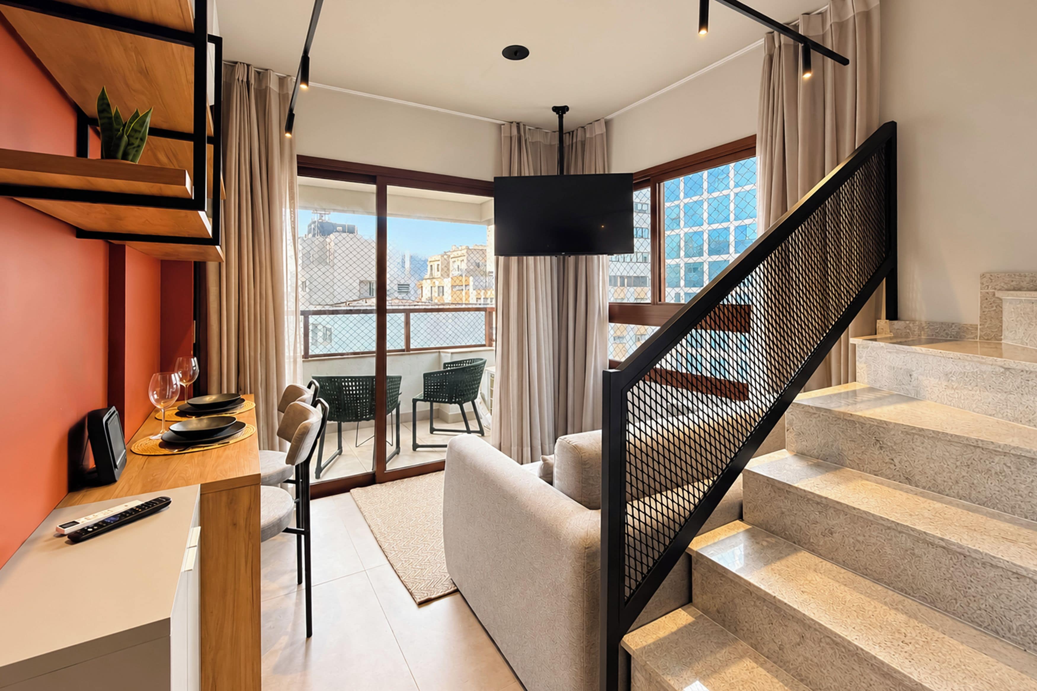 A modern living space with a staircase, a dining area, and a view of the city.