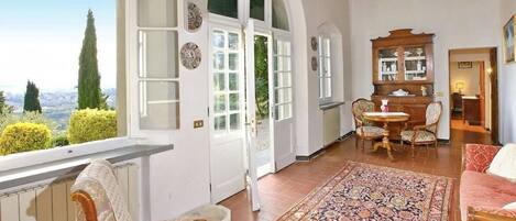 A spacious room with a large window, a patterned rug, and a wooden cabinet.
