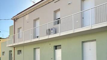 Ein zweistöckiges Gebäude mit Balkon, Garagentor und einem Technikschacht.