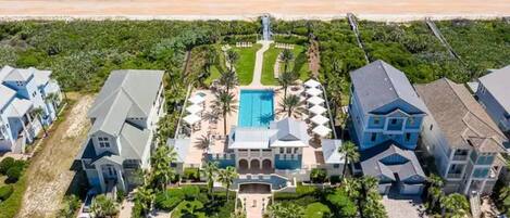 Un resort con piscina central, varias construcciones y vista al mar.