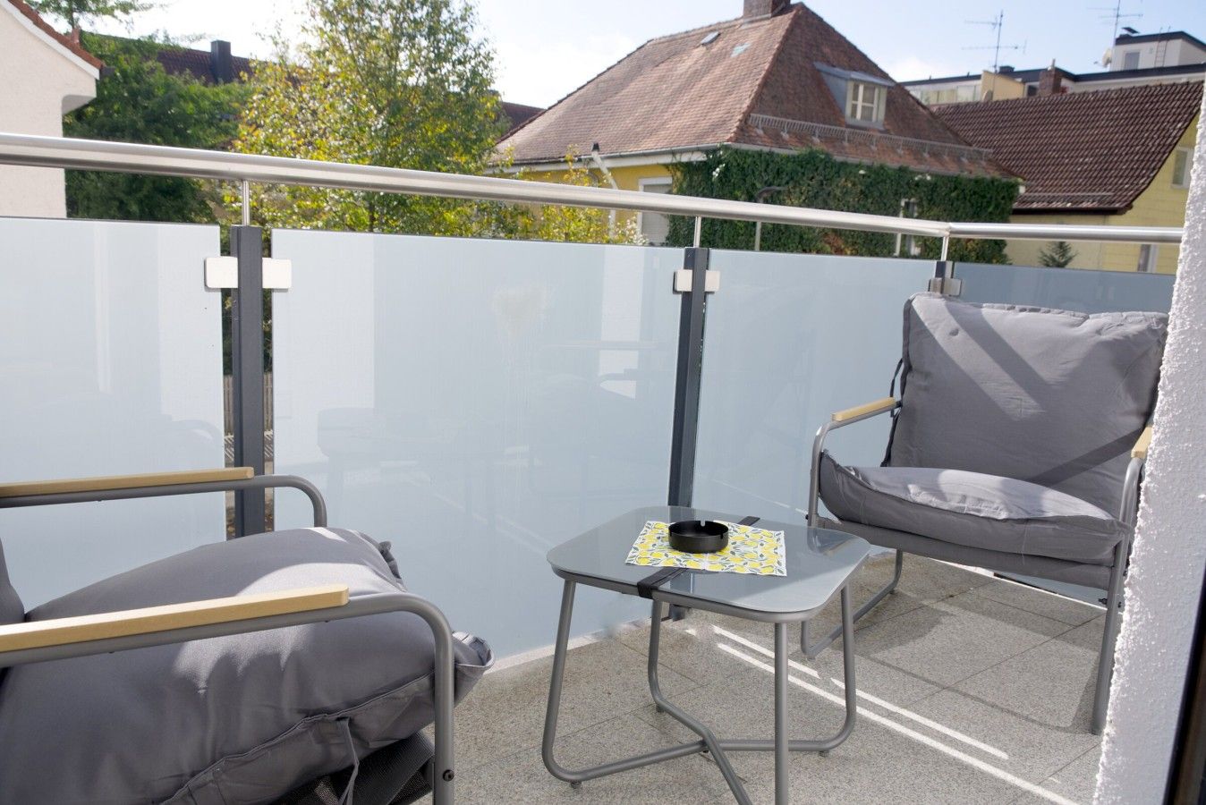 A balcony with a chair, a small table, and a railing.