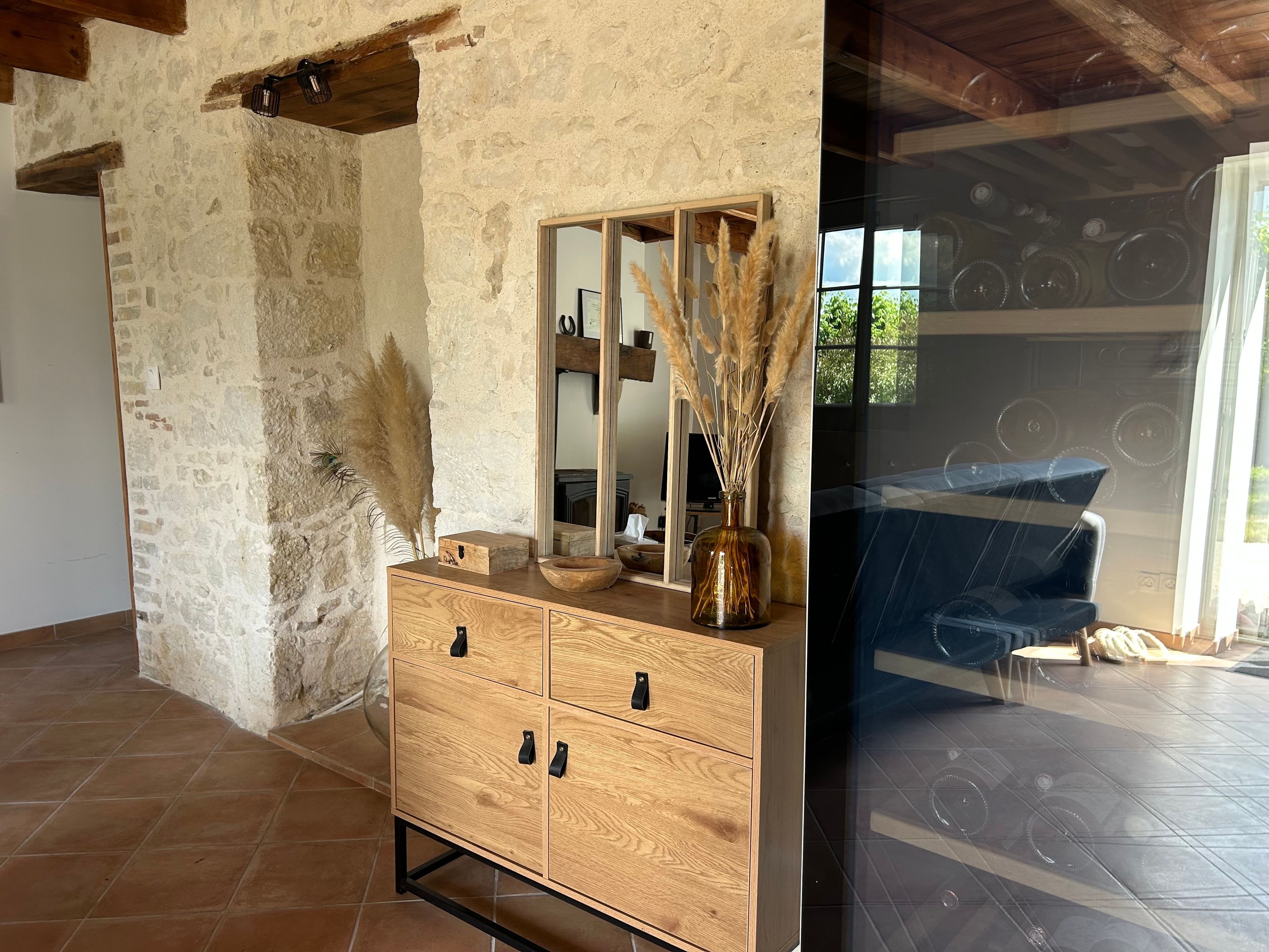 A wooden dresser with drawers, a mirror, and a vase with dried plants.