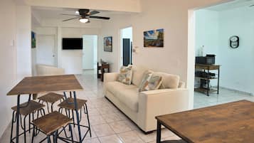 A spacious living area with a sofa, coffee table, and dining table with chairs.