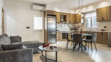 Een moderne keuken met houten kastjes, een roestvrijstalen koelkast en een eethoek met een ronde tafel en stoelen.