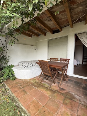 A patio area with a wooden table and chairs, a white cushioned bench, and a tiled floor. - Casa del Viento · Vista al lago y terraza (Valle de Bravo)