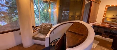 A curved staircase leading to a seating area with a view of trees through large windows.