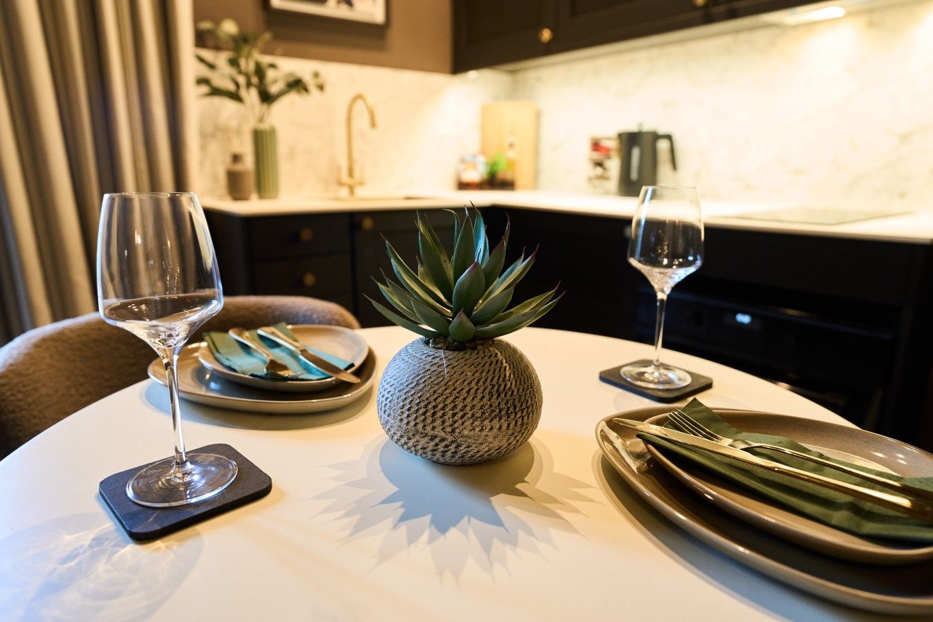 Una mesa de comedor con una piña como centro de mesa, dos copas de vino y platos.