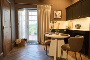 A kitchen with a dining table, chairs, a sink, and a view of the outdoors. - Stylish Terrace Suite in South Downs Near Arundel (Warningcamp)