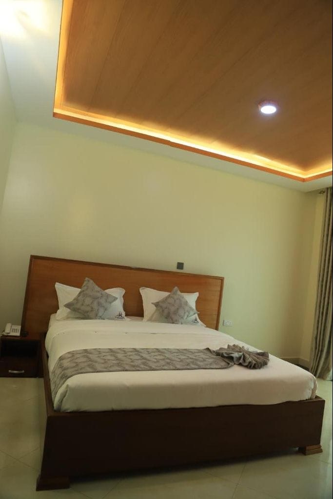 A hotel room with a large bed, a wooden headboard, and a ceiling light.