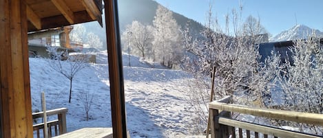 Een houten terras met uitzicht op een besneeuwd landschap en bergen.