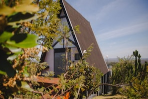 Un bâtiment moderne doté d’un toit en pente, entouré de végétation.