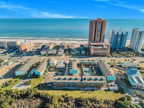 Complejo hotelero frente al mar con varias edificaciones, estacionamiento y vistas a la playa.
