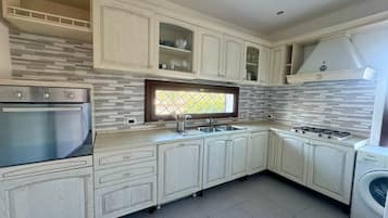 A kitchen with a built-in oven, a gas stove, a sink, and a window with a view.