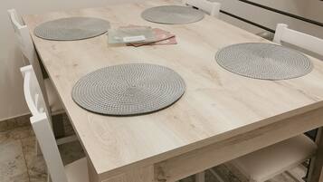 Een houten eettafel met vier placemats en enkele gevouwen servetten.