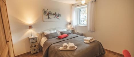 Une chambre à coucher comprenant un lit, des tables de chevet, une fenêtre et une œuvre d’art accrochée au mur.