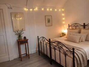 Ein Schlafzimmer mit Bett, Nachttisch, Lampe, Spiegel und Lichterkette.